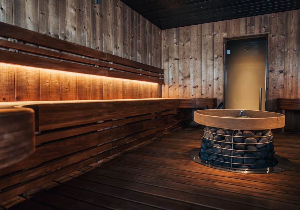 Wooden banya room with bench seating and a central heater