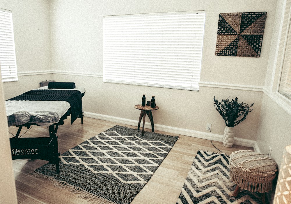 Treatment room with a made-up massage table, a patterned rug and folded towels