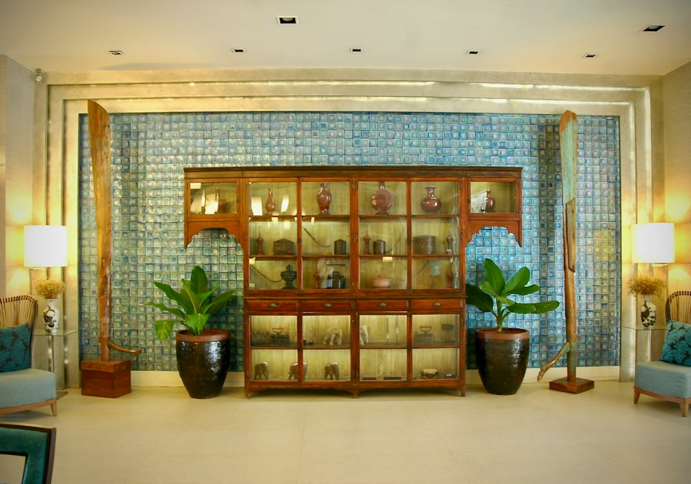 Relaxation area with armchairs, tall planters and a lit display cabinet