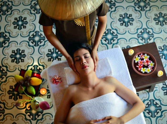 Overhead view of a shoulder massage beside a bowl of floating flowers