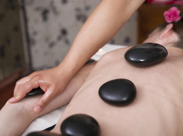 Row of smooth dark stones resting along a guest’s back during a hot stone treatment